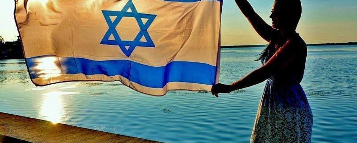 Woman waves Israei flag with a view of the sea