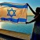 Woman waves Israei flag with a view of the sea
