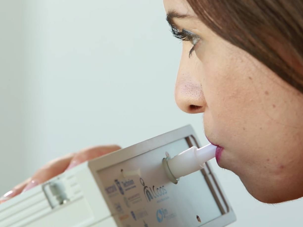 Woman breathing into device that can detect early stages of disease