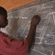 An African teenager solving a math question in a blackboard linked to university of the people