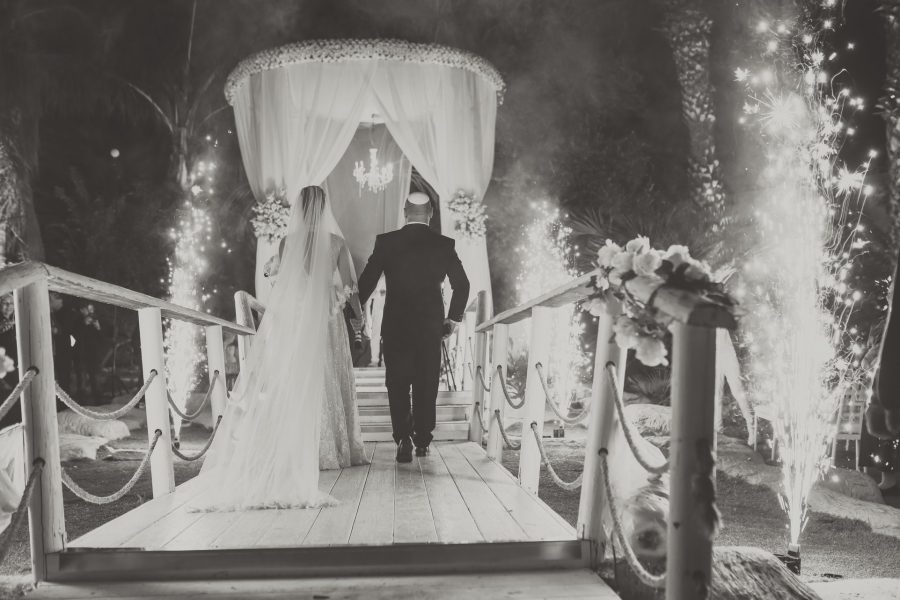 bride and groom in black and white rear photo walking to the chupah